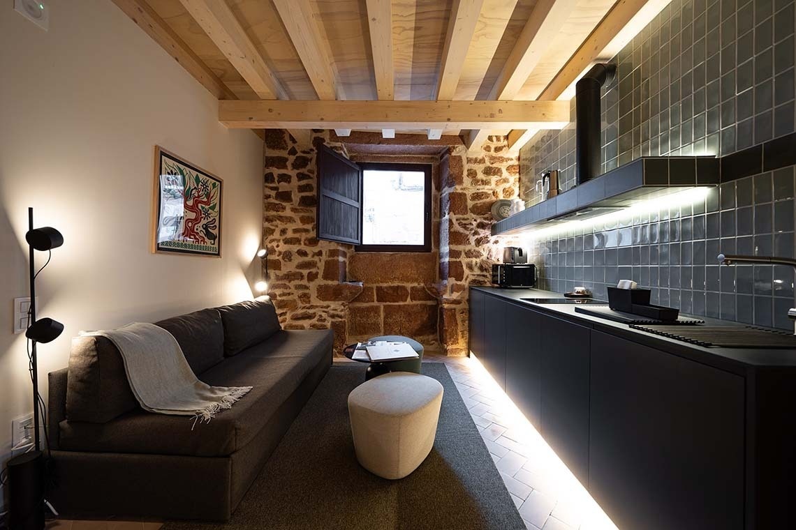 Salón y cocina de Apartamentos Vilafamés Antic Palau con sofá y vigas de madera.