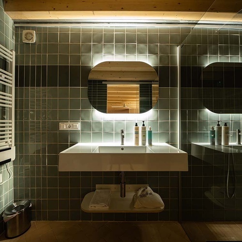 Modern bathroom at Apartamentos Vilafames Antic Palau, featuring a floating vanity and backlit mirror.
