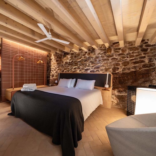 Bedroom with wooden beams and stone walls at Apartamentos Vilafames Antic Palau.