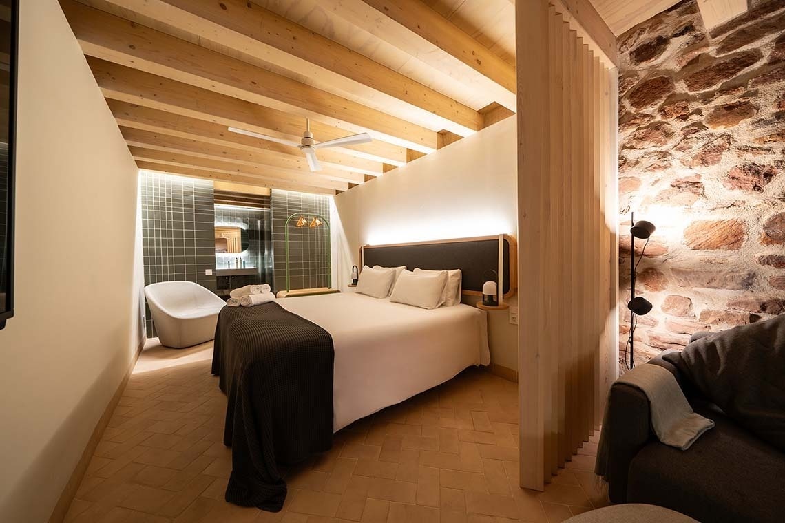 Suite rústica con cama cómoda y paredes de piedra en Apartamentos Vilafames Antic Palau.