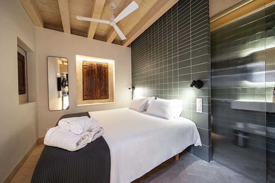 Habitación moderna en Apartamentos Vilafames Antic Palau con cama confortable y ducha de cristal.