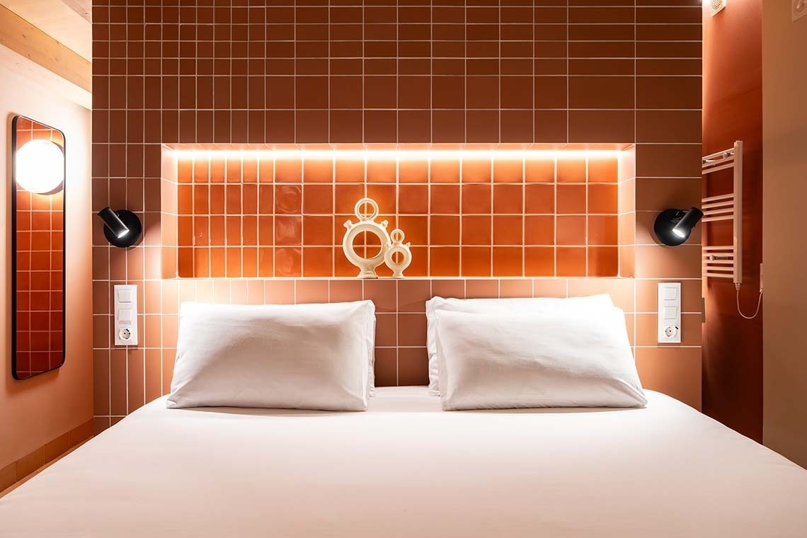 Cama matrimonial con dos almohadas blancas y detalles decorativos en Apartamentos Vilafames Antic Palau.
