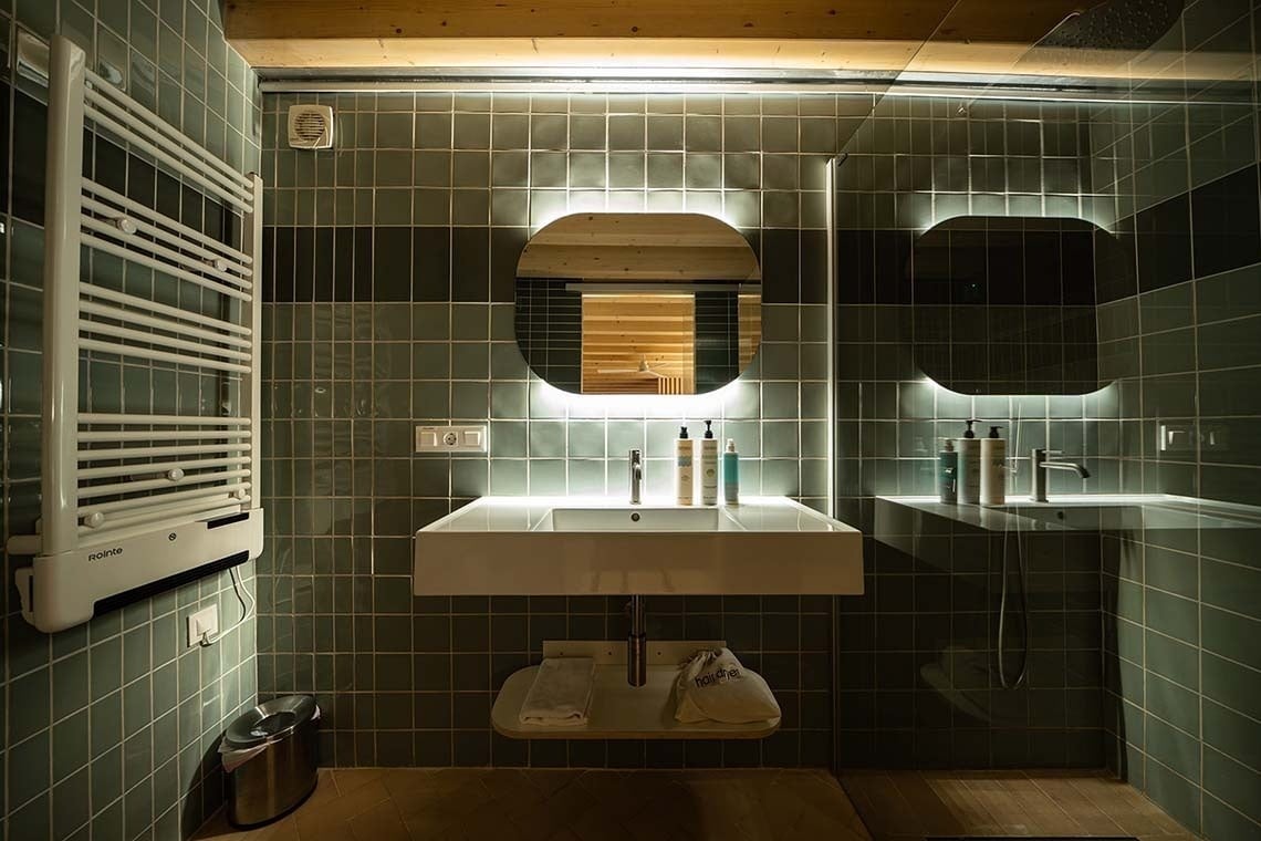 Baño moderno en Apartamentos Vilafames Antic Palau, con lavabo flotante y espejo iluminado.
