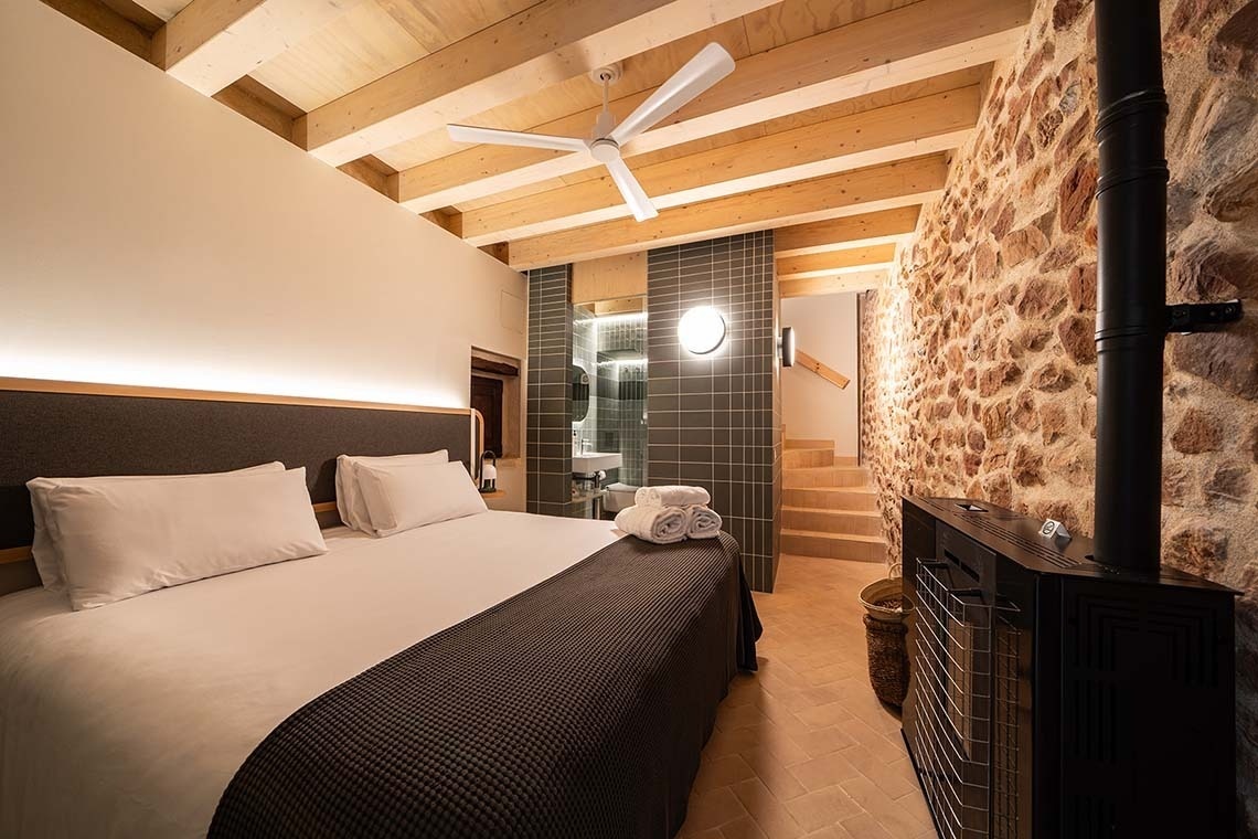 Suite acogedora en Apartamentos Vilafames Antic Palau con piedra rústica y vigas de madera.