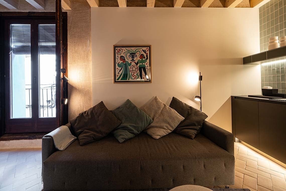 Sofá acogedor en Apartamentos Vilafames Antic Palau, con cuadro colorido y luz tenue.
