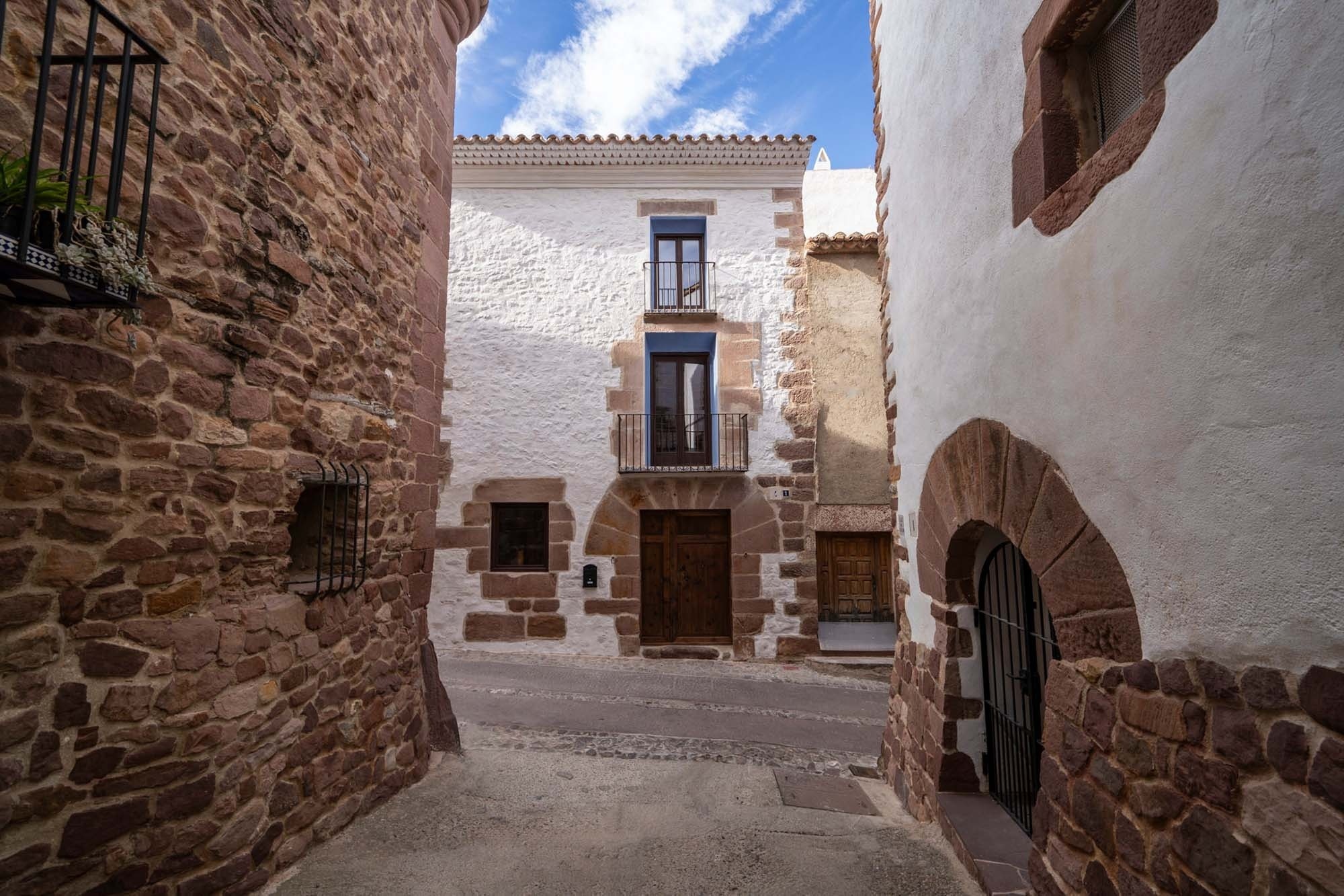 Acogedor callejón con fachadas blancas y de piedra. Contacto | Apartments Antic Palau | Vilafamés, Castellón.