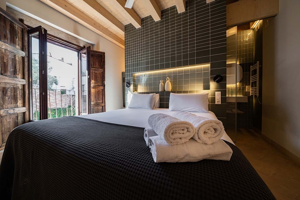 Cama matrimonial con estilo moderno y balcón en Apartamentos Vilafames Antic Palau.