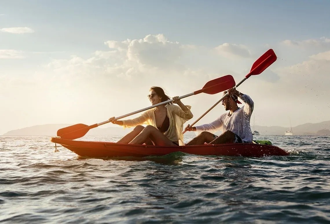 un hombre y una mujer están remando en un kayak rojo en el océano