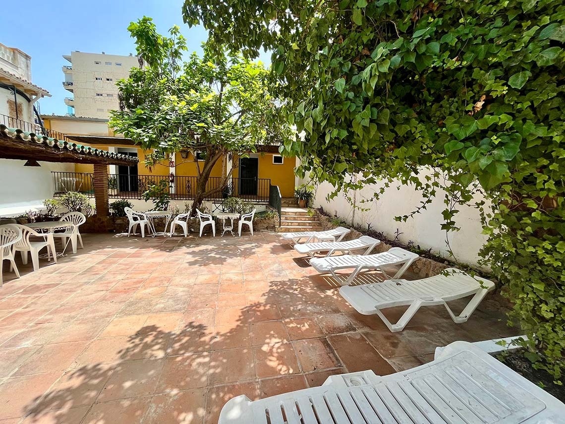 Sunny patio at Hotel Villa Albero with sun loungers and outdoor tables.