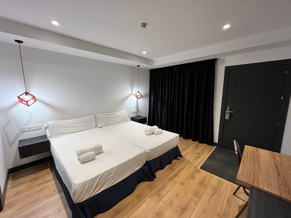 Double room at Hotel Villa Albero, modern and bright, with two beds and a desk.