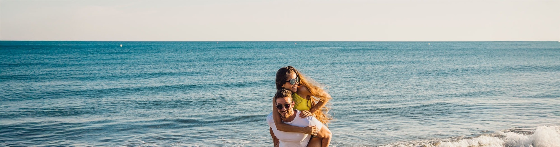 un hombre lleva a una mujer en sus hombros en la playa