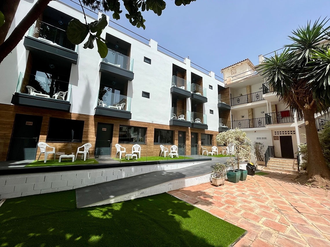 Hotel Villa Albero: white facades with balconies, patios and palm trees.