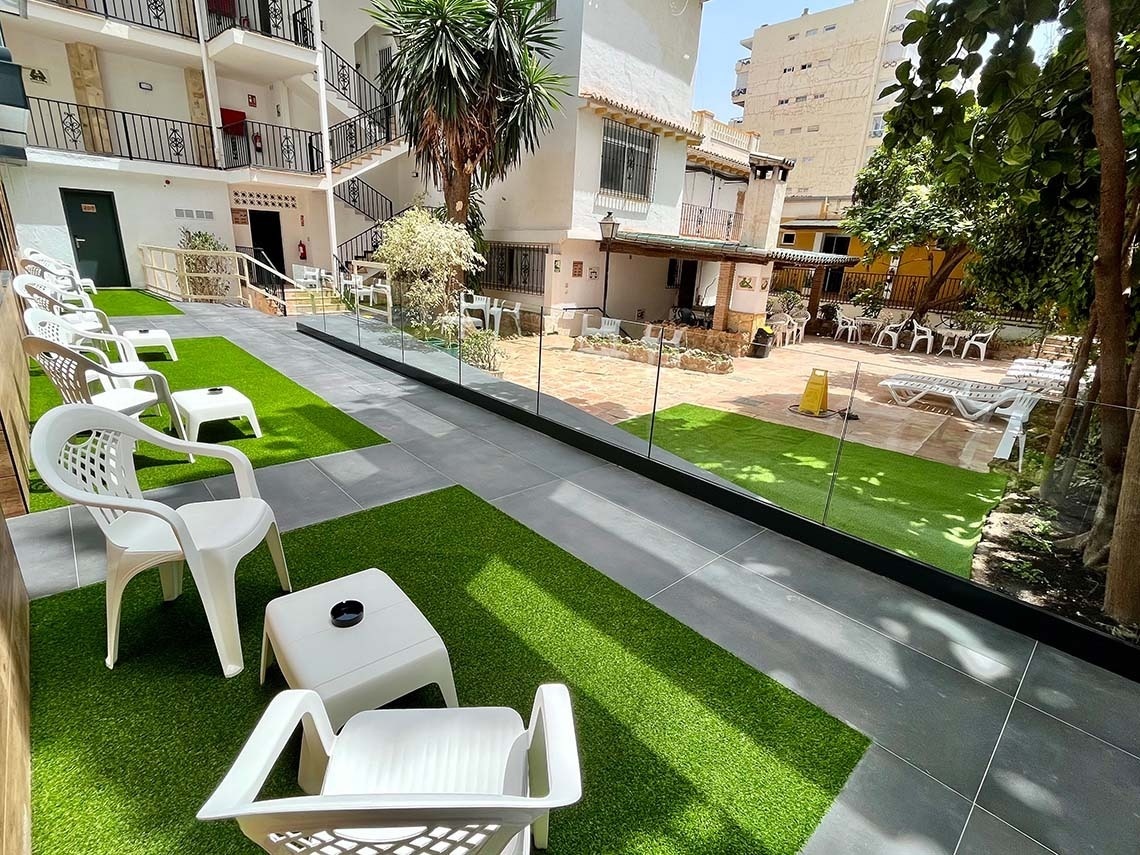 Hotel Villa Albero: Courtyard with artificial grass, chairs, and tables.