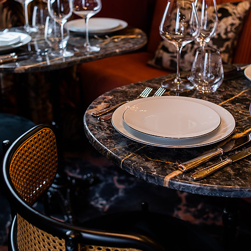 Elegante mesa en Villa Dorothea con vajilla de porcelana, copas de vino y cubiertos.