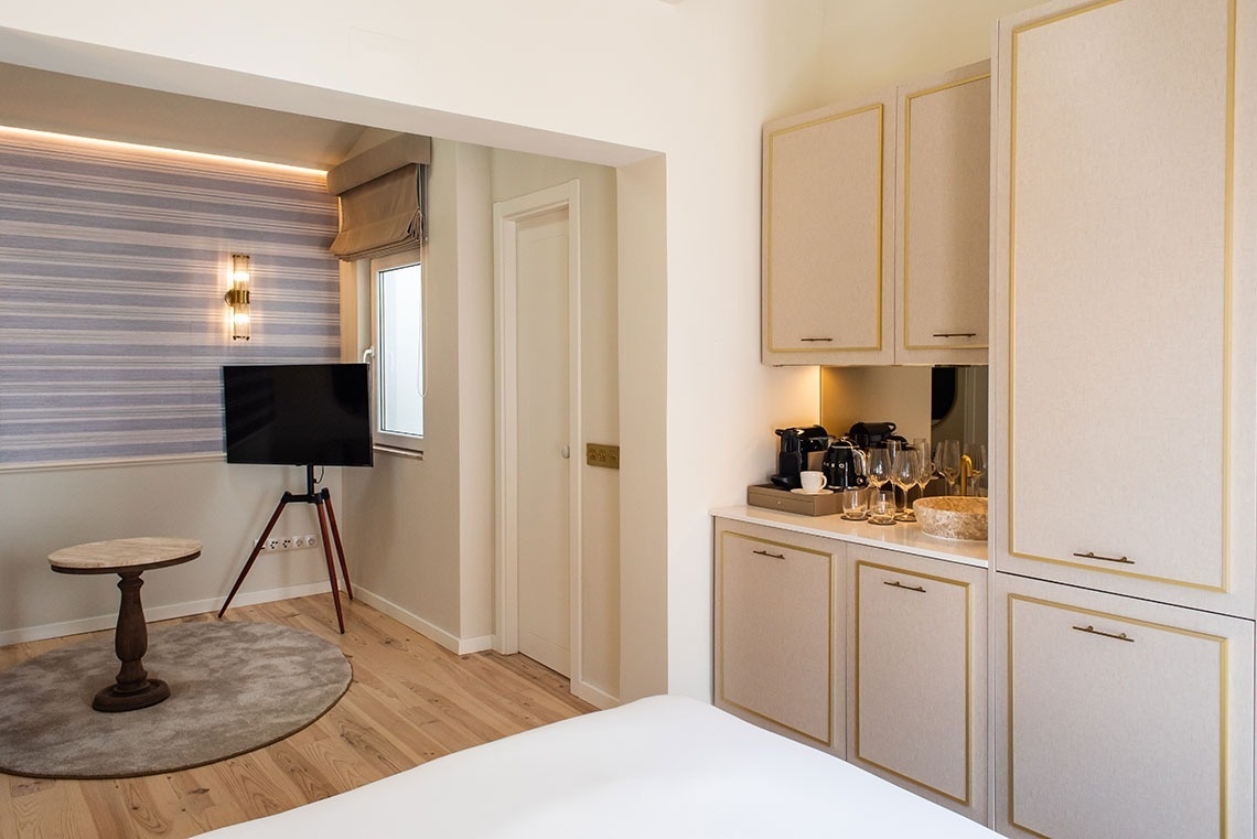 Quarto de hotel moderno e elegante com TV, área de café e armários embutidos.