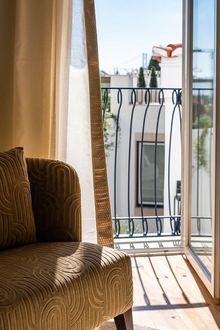 Quarto de hotel confortável com varanda e vista para a cidade de Lisboa e ponte.