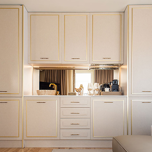 Moderna cocina de Villa Dorothea con armarios color crema y detalles dorados.