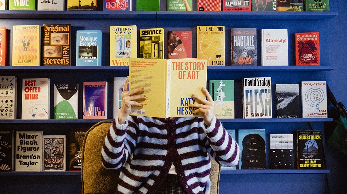 Prateleira de livros em uma livraria, a pessoa está lendo 