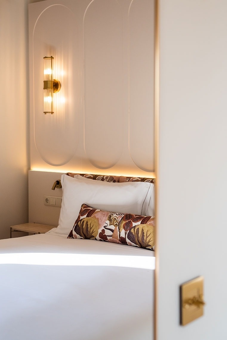 Quarto de hotel moderno com cama confortável, cabeceira iluminada e almofada decorativa. Ambiente acolhedor.