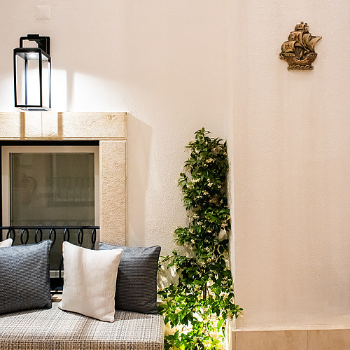 Sofá exterior acogedor en Villa Dorothea con plantas exuberantes y decoración náutica.