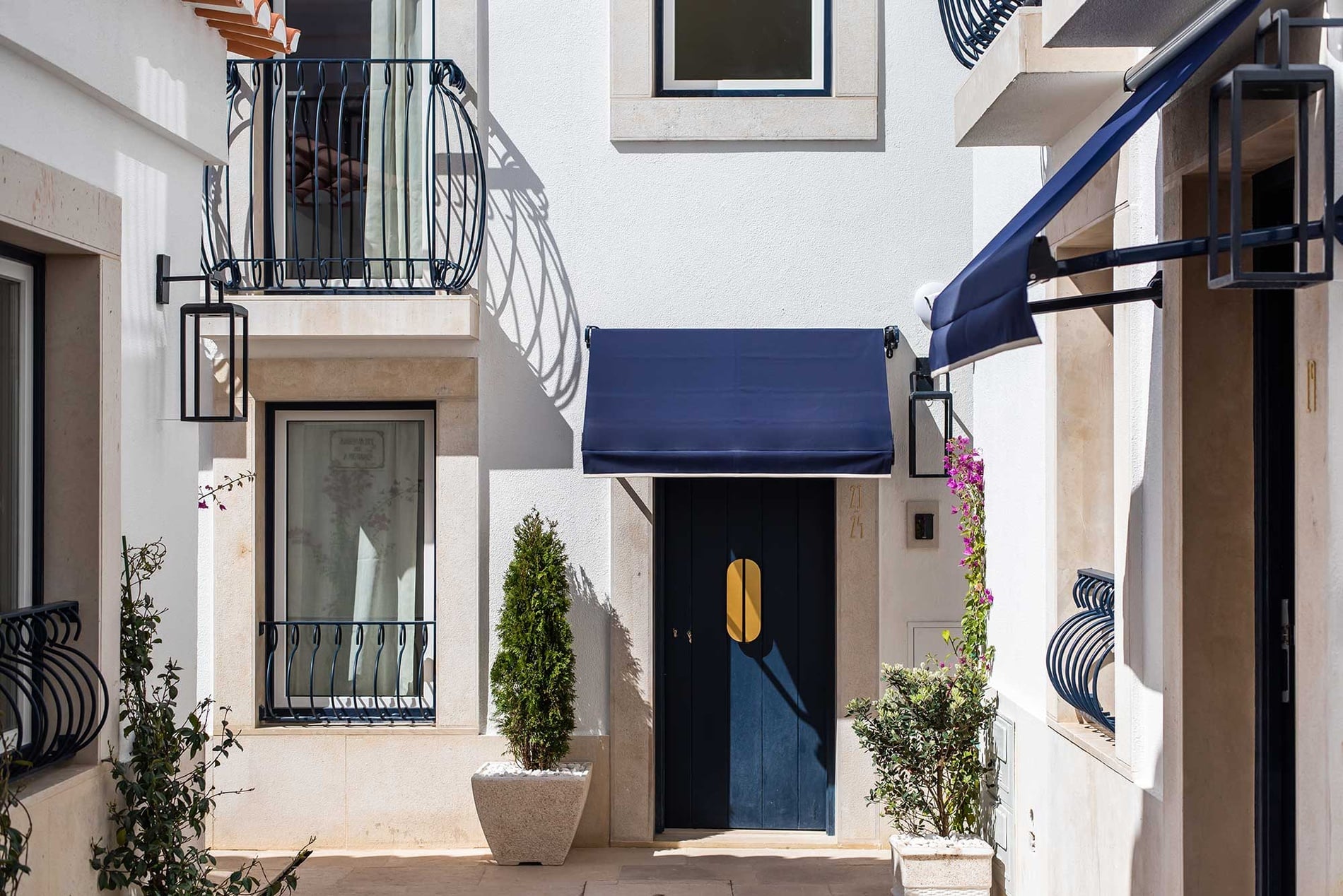Puerta azul de Villa Dorothea, toldo azul, balcón, ventana y vegetación.