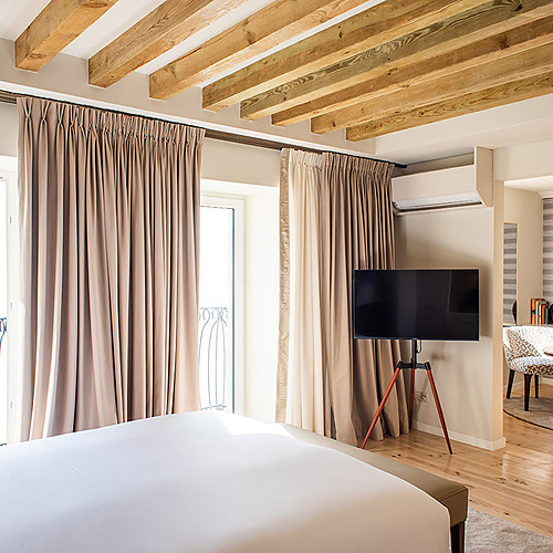 Suite moderna en Villa Dorothea con vigas de madera y TV de pantalla plana.