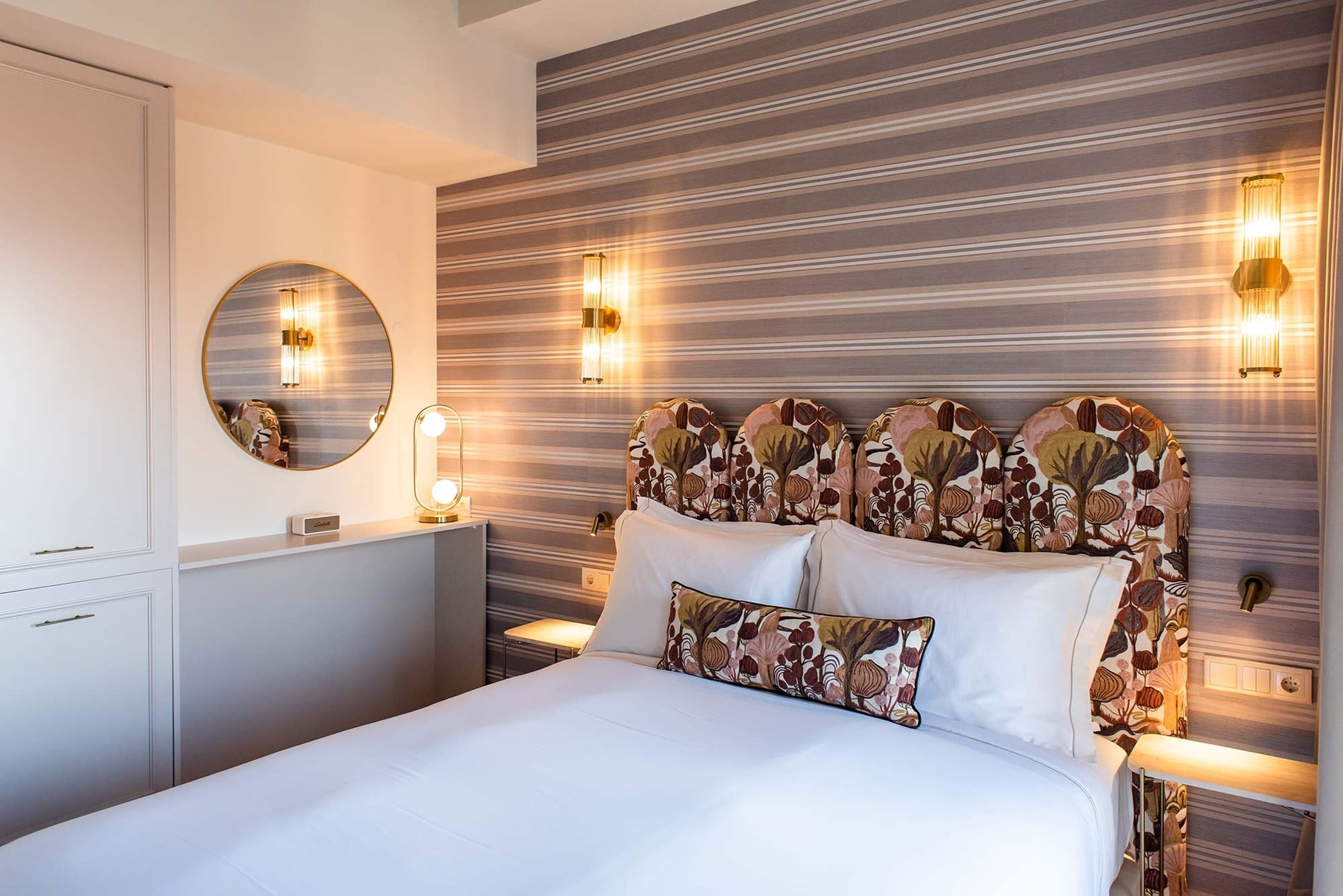 Elegante habitación en Villa Dorothea con cama doble, lámparas de pared y papel tapiz rayado.