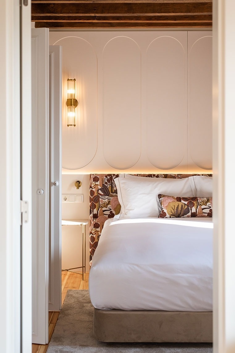 Quarto de hotel moderno com cabeceira estampada, iluminação ambiente e decoração elegante.