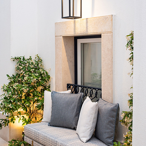 Banqueta exterior decorada con cojines y flores en Villa Dorothea.