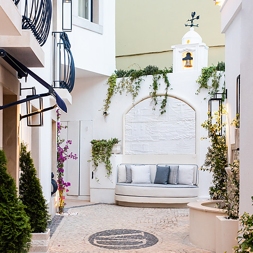 Villa Dorothea: Acogedor patio con sofá curvo, plantas y campanario.