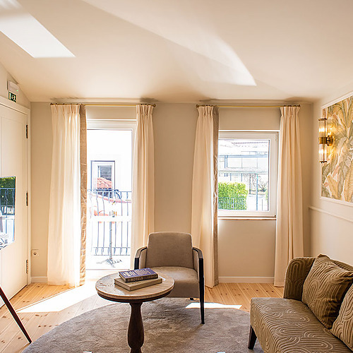 Elegante salón de Villa Dorothea con sofá, sillón y balcón.