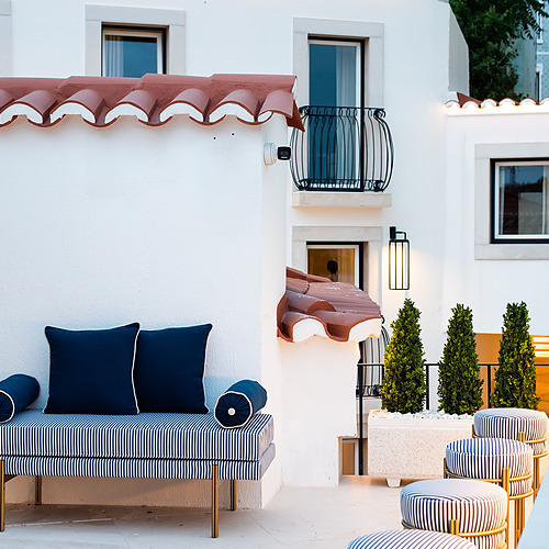 Elegante terraza exterior de Villa Dorothea con muebles a rayas y plantas verdes.