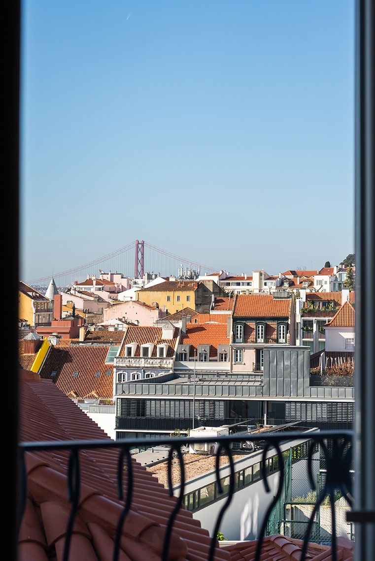Vista panorâmica de Lisboa do hotel: Ponte 25 de Abril e telhados tradicionais ao sol.