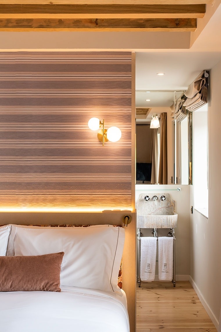 Quarto de hotel com design único, cama, iluminação ambiente e área de lavatório em pedra.