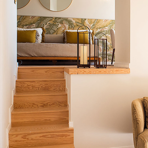 Escaleras de madera hacia suite en Villa Dorothea, con decoraciones tropicales y luminarias.