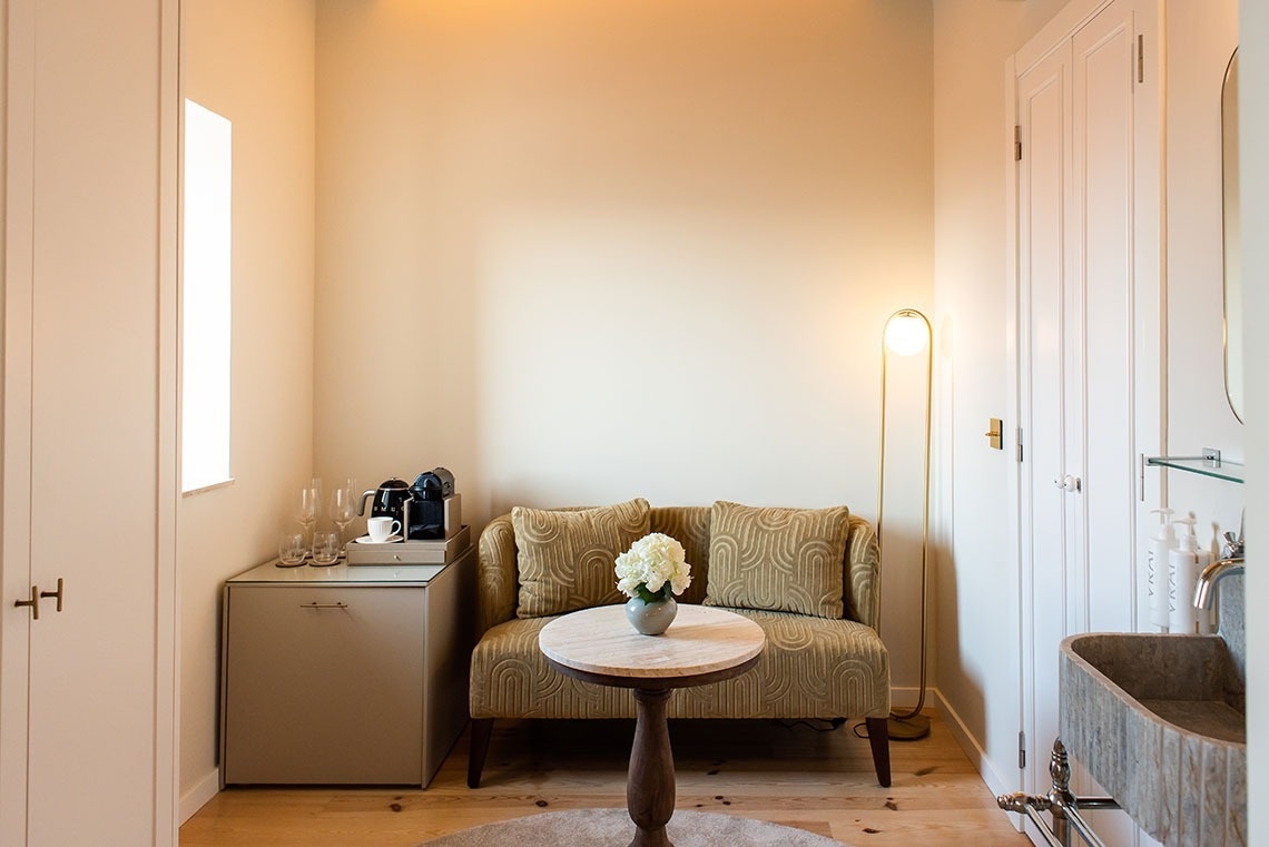 Quarto de hotel aconchegante com sofá, mesa de café e máquina Nespresso. Design interior luxuoso.