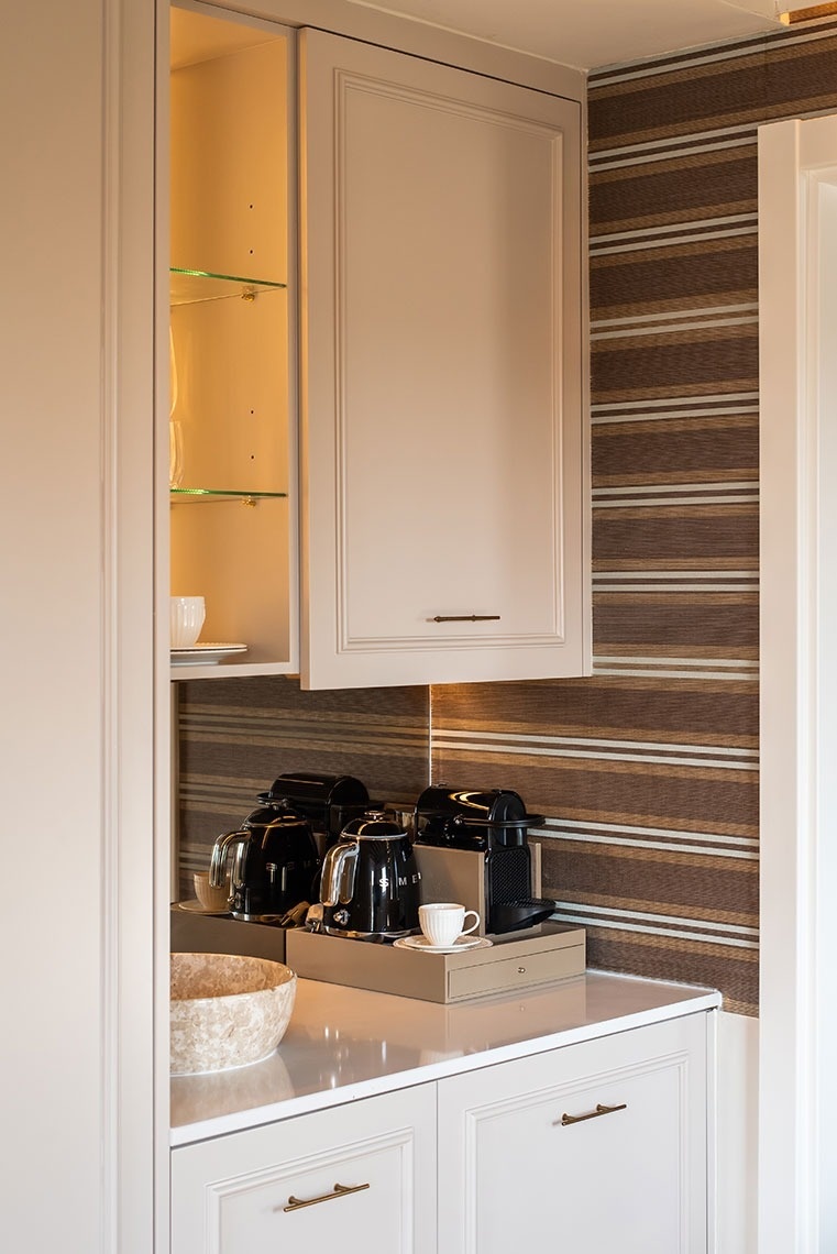 Estação de café deluxe em quarto de hotel: máquinas Nespresso, chaleiras Smeg e design sofisticado.