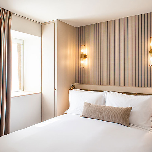 Cama matrimonial en Villa Dorothea con almohadas blancas y cojín beige.