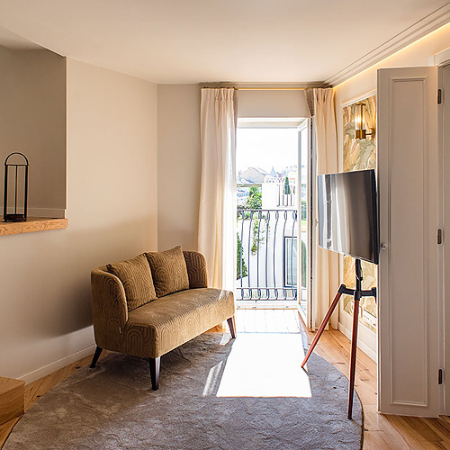Elegante salón con sofá, TV y balcón en Villa Dorothea.
