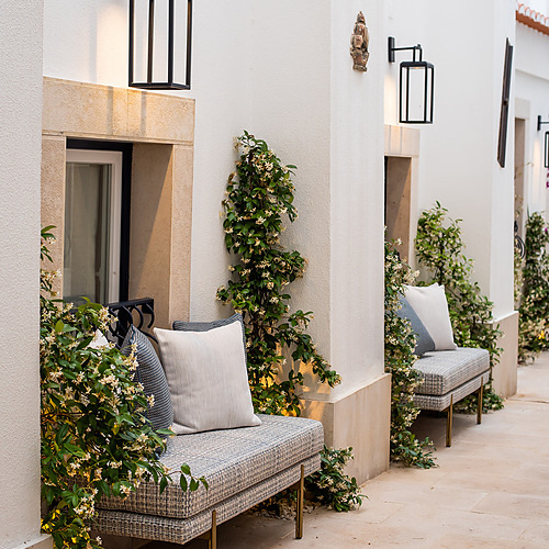 Sofá exterior en Villa Dorothea con plantas floridas.