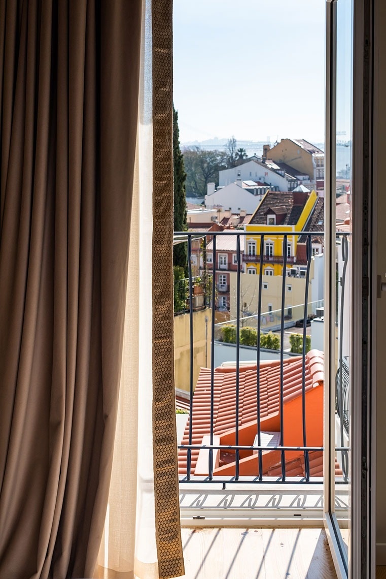 Varanda de hotel em Lisboa com vista panorâmica da cidade e rio Tejo.