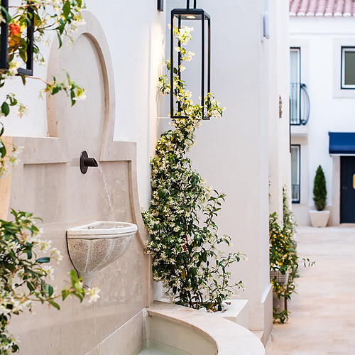 Fuente de agua y flores en Villa Dorothea, un destino mediterráneo encantador.