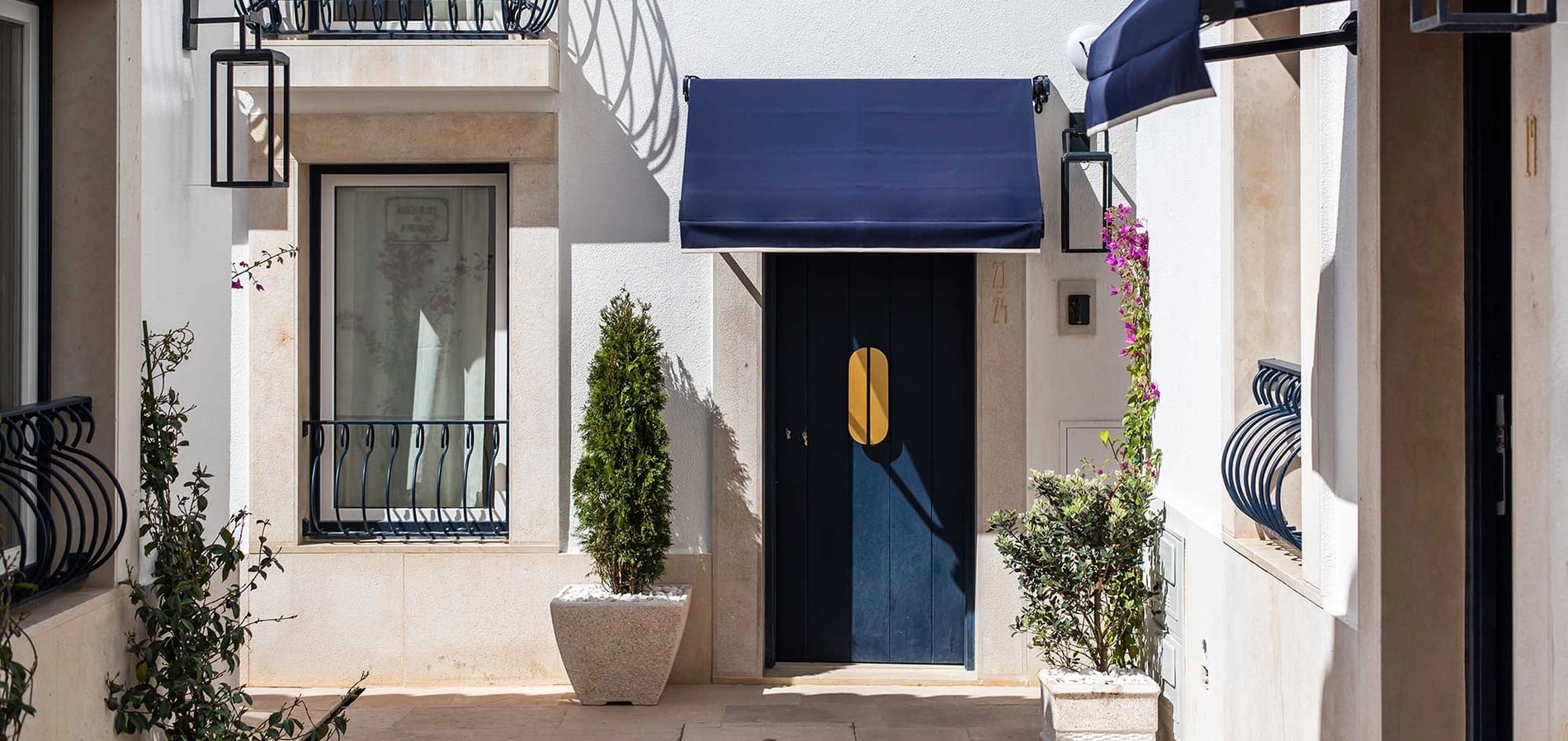 Fachada de Villa Dorothea con puerta azul y toldo. Decoración elegante.