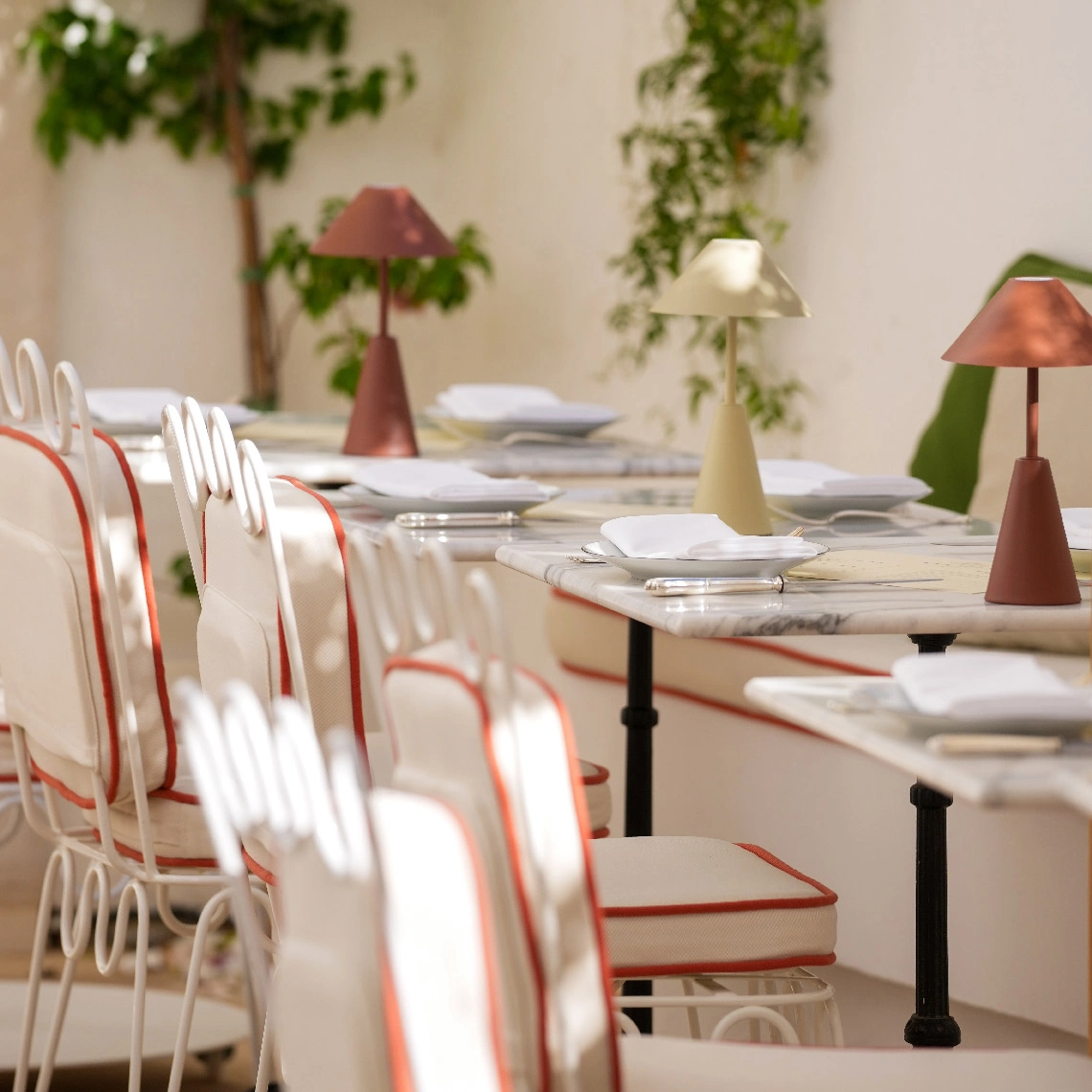 Mesas listas en restaurante de hotel, Villa Dorothea con lámparas y sillas elegantes.