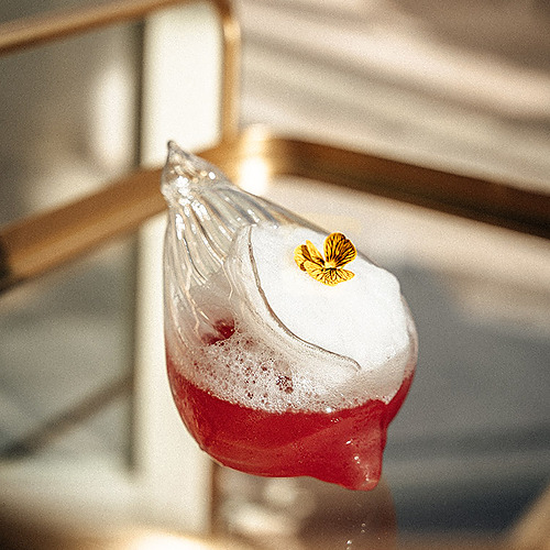 Cóctel artístico con flor comestible en vaso único, perfecto para Villa Dorothea.