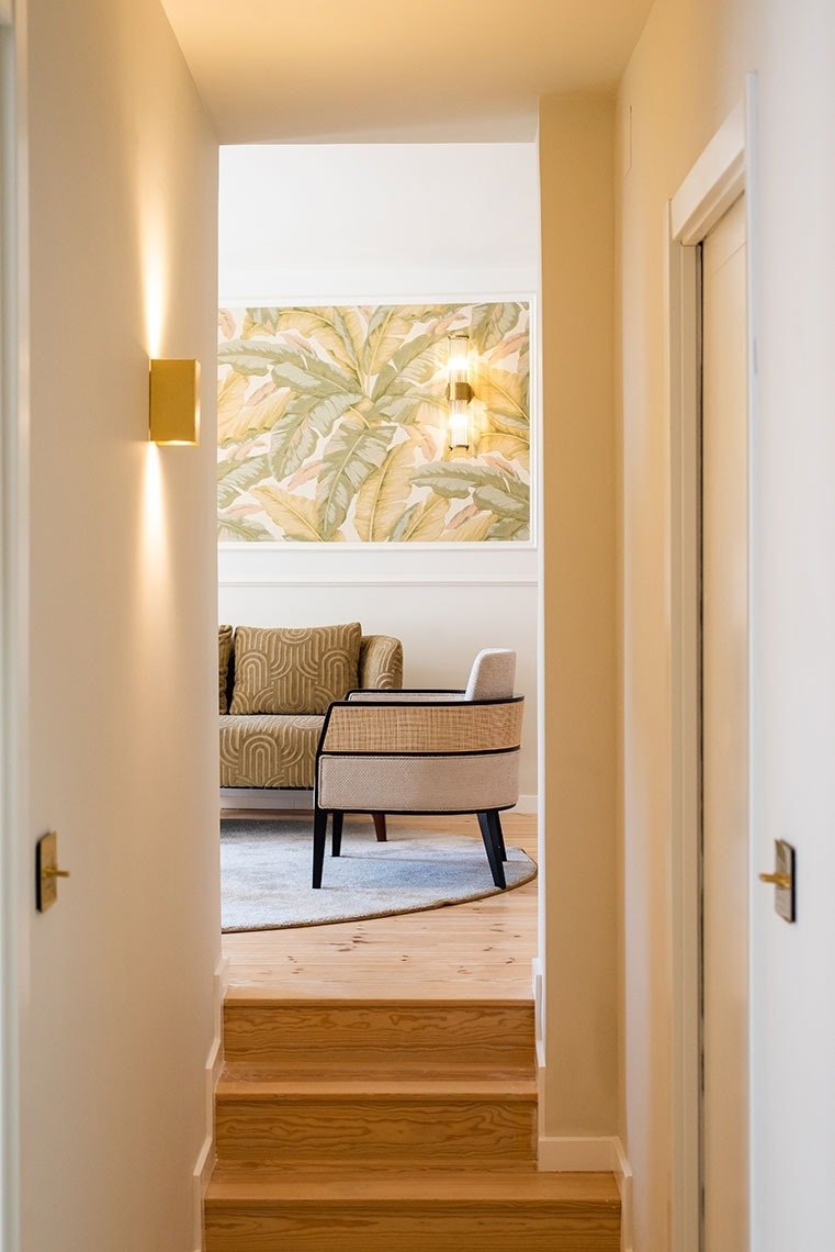 Área de estar convidativa em hotel com papel de parede tropical, mobiliário moderno e iluminação acolhedora.