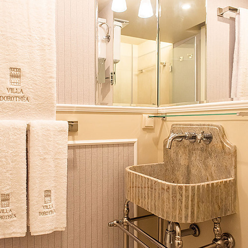 Baño elegante en Villa Dorothea con toallas bordadas y lavabo de mármol.