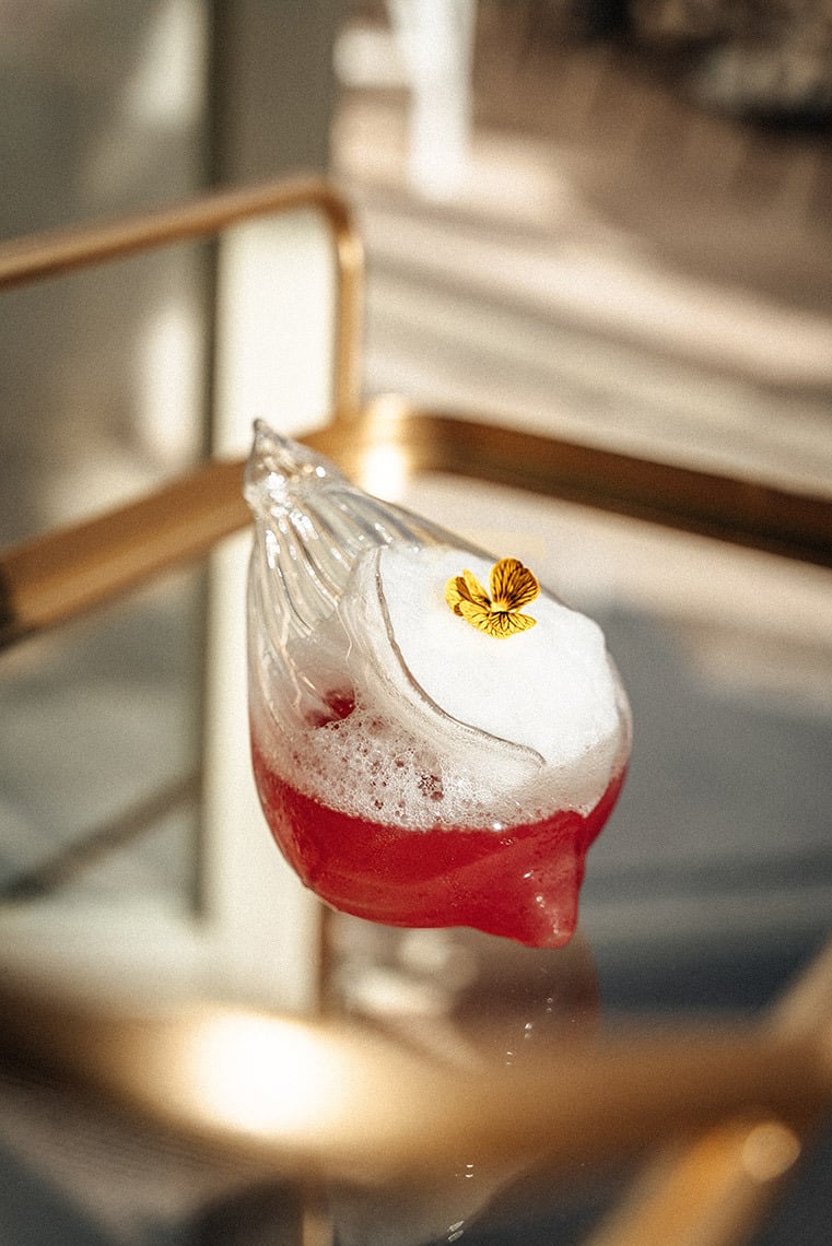 Elegant cocktail served in a unique glass with a floral garnish, perfect for a Villa Dorothea stay.