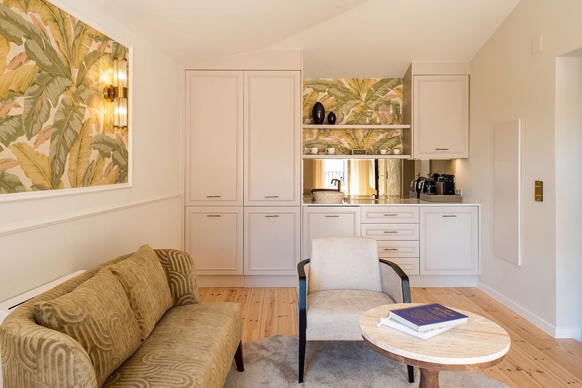 Suíte de hotel elegante com kitchenette, área de estar confortável e decoração tropical.