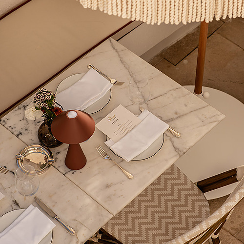 Mesa de mármol en un restaurante, lista para cenar con Villa Dorothea.